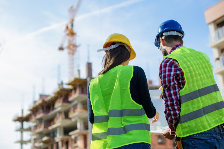 co-workers wearing safety vests and hard hats at construstion site improving employee workplace safety