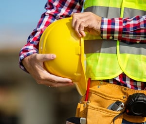 man holding hard hat and wearing safety vest being a safe employee on-site