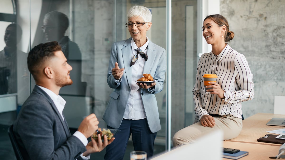 Colleagues share a laugh over coffee and snacks during a relaxed office break