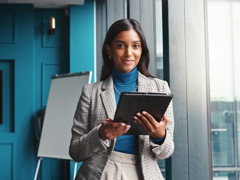 Confident HR leader holding a tablet and smiling in a modern office