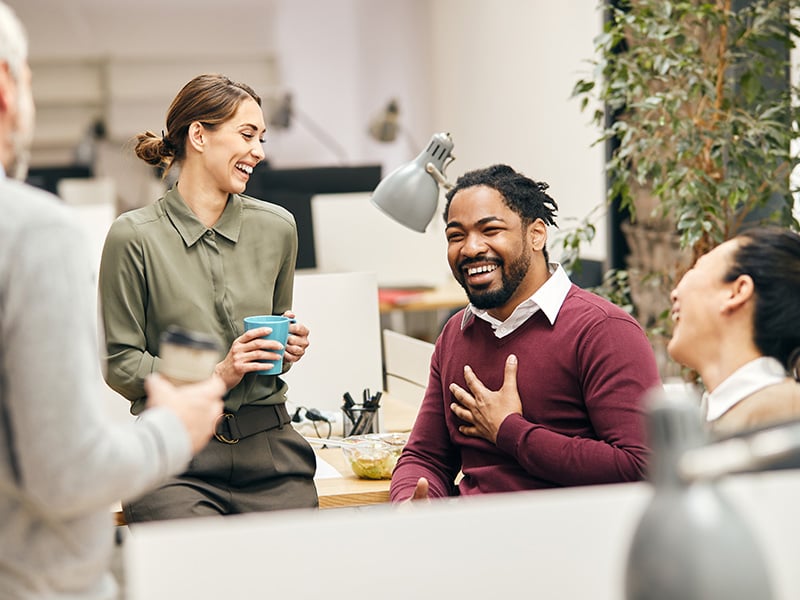 Diverse team of coworkers laughing and connecting during a casual office moment
