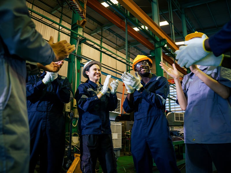 Diverse team of employees applaud together, celebrating a shared workplace achievement