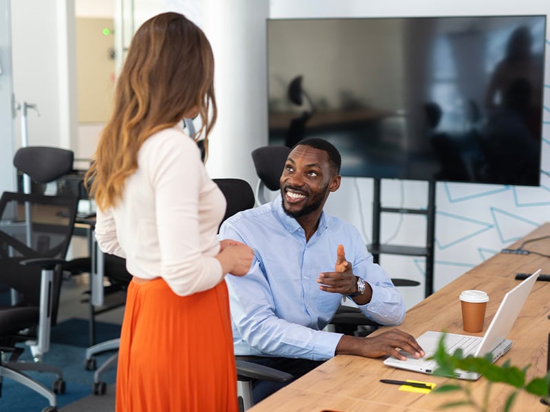 Employee cheerfully recognizing a coworker during a casual office conversation