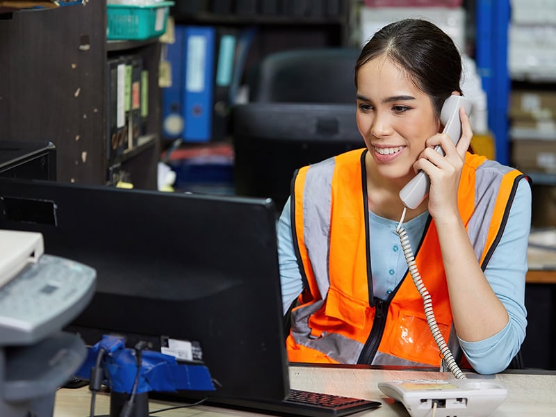 Employee in safety vest answers the phone, delivering the service worth recognizing