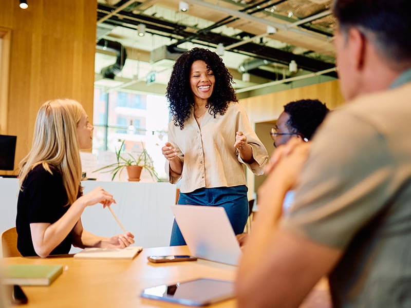 Energetic team leader smiling and engaging her team during an office meeting