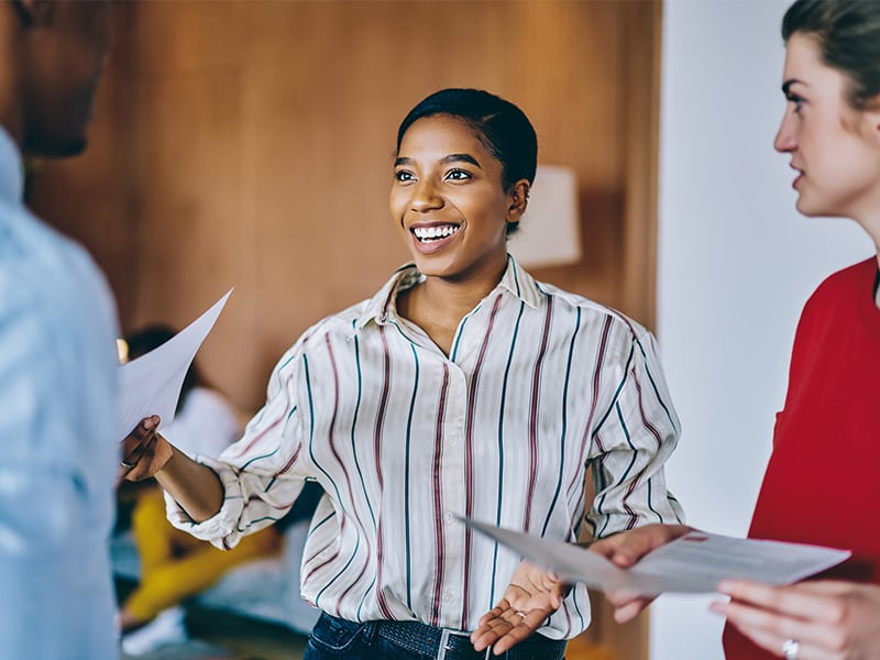 Energized employee laughing and engaging with teammates during a work discussion