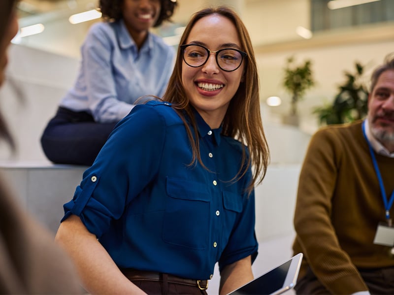 Engaged employee smiling warmly during a collaborative team gathering at the office