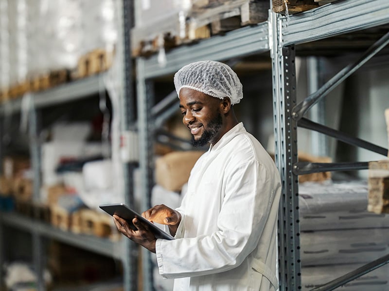 Food production team in hairnets and masks reviews quality checks together