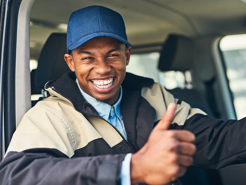 Happy delivery driver giving a thumbs up from inside his vehicle