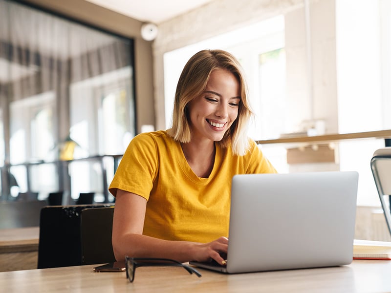 Happy employee smiling while working on her laptop in a bright office