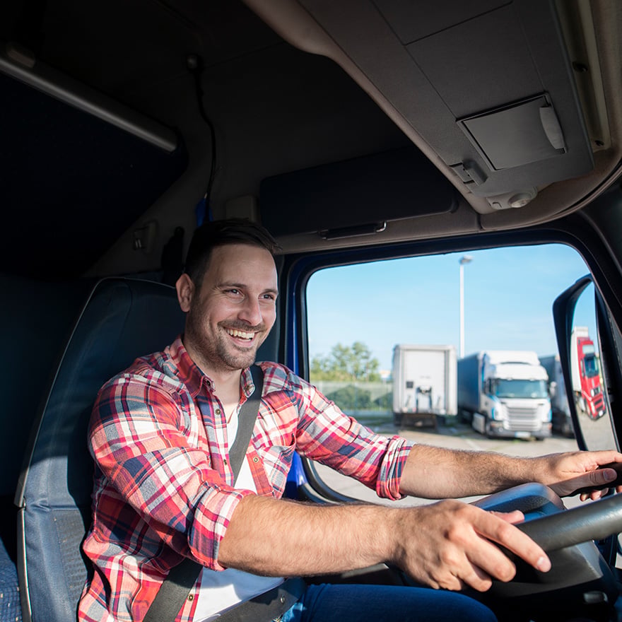Happy truck driver smiling from behind the wheel in his cab