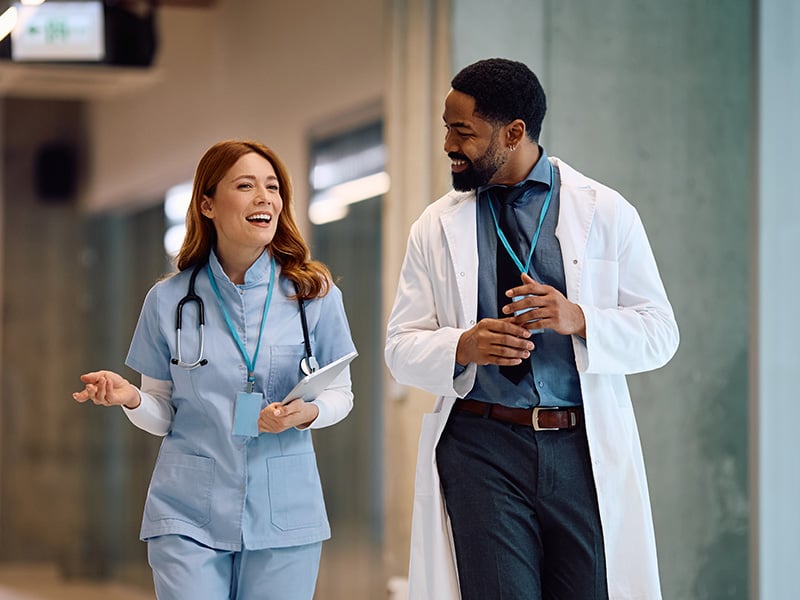 Nurse and doctor walking together and sharing a happy moment at work