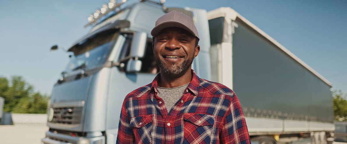 Proud truck driver smiling confidently in front of his vehicle