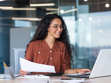 Smiling employee reviewing recognition results on her laptop at her desk