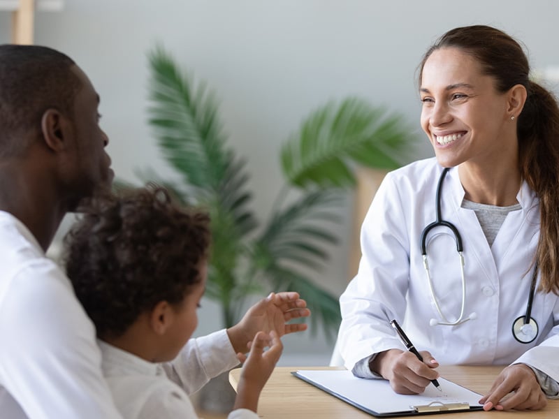 Smiling physician connects warmly with a family during a caring appointment