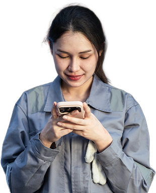 Smiling technician in coveralls checks her phone in a workshop, staying connected on the job