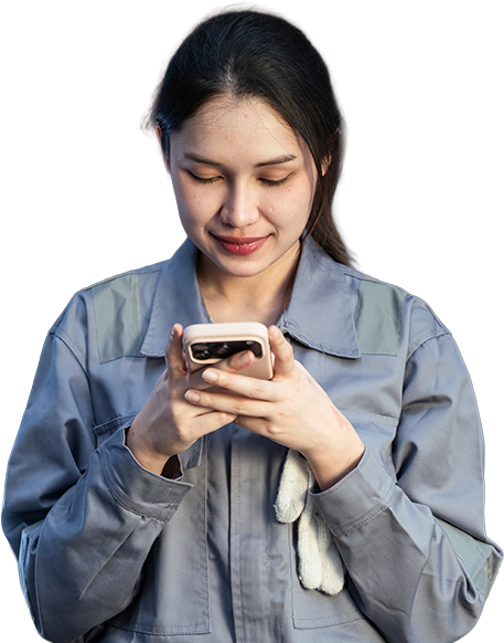 Smiling technician in coveralls checks her phone in a workshop, staying connected on the job