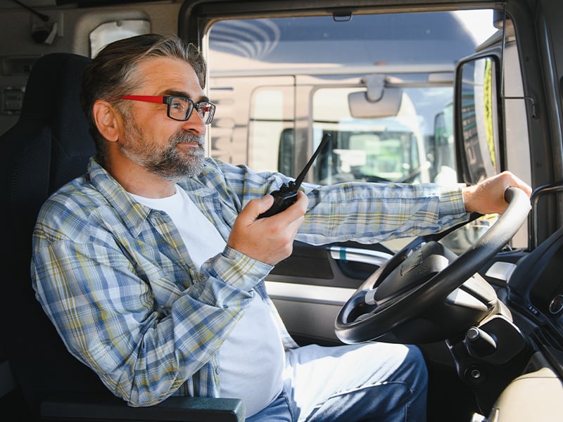 Truck driver using a radio communicator from inside his cab