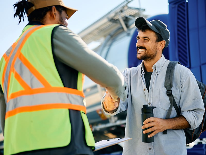Two logistics workers sharing a friendly handshake in a transportation yard