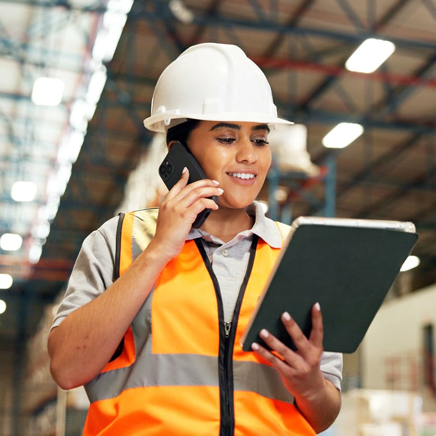 Warehouse supervisor multitasks with a phone call and tablet while managing operations