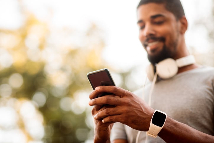 A man smiling, accessing his phone